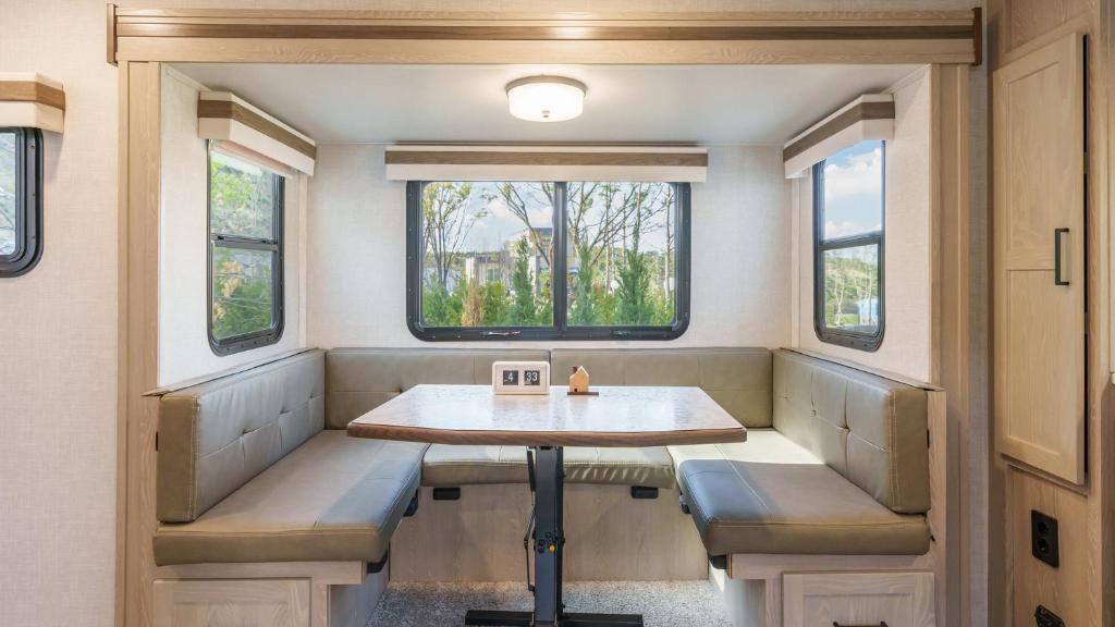 a dining room with a table and two windows at Sokcho Supuro Caravan in Sokcho