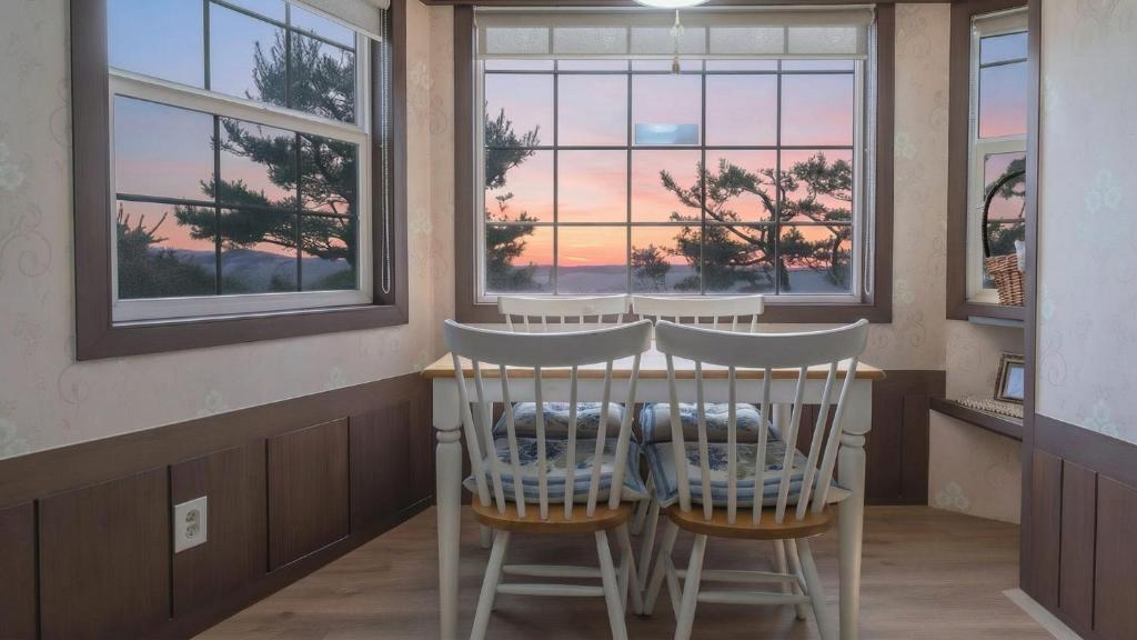 a dining room with a table and chairs and windows at Ganghwa Western Beach Pension in Incheon