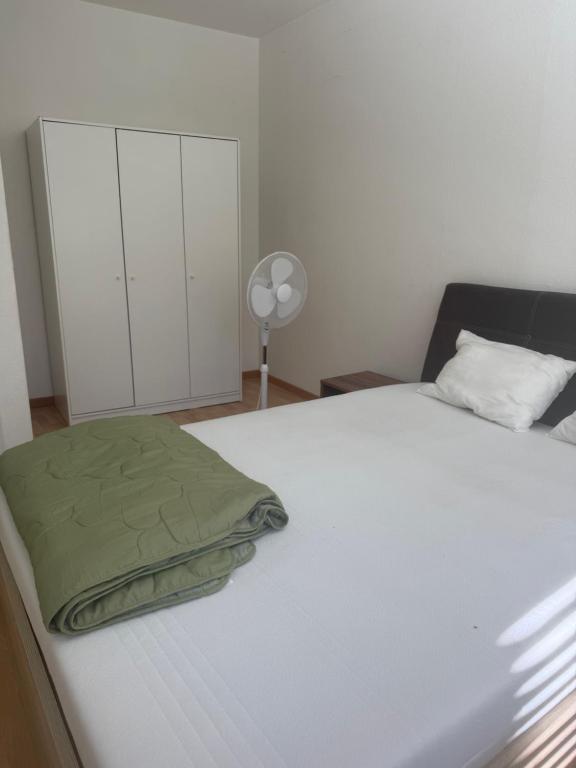 a white bed with a green blanket on it at Basel Shared Apartment in Basel