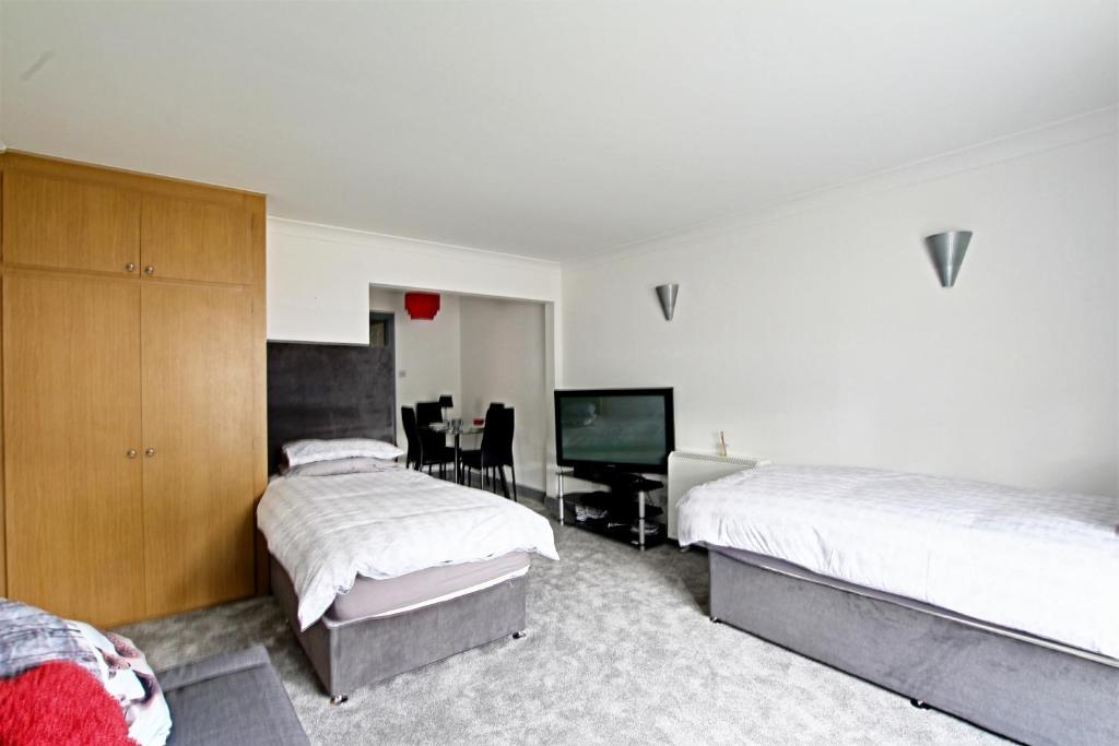 um quarto com 2 camas e uma televisão de ecrã plano em The Willows em Crawley