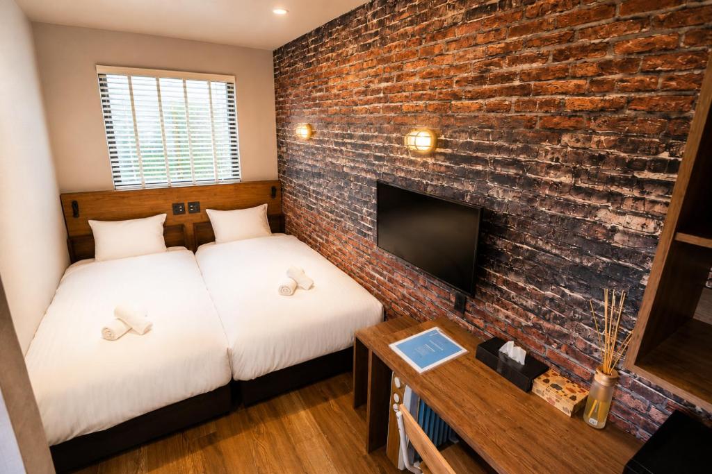 two beds in a room with a brick wall at KAJAhause in Osaka