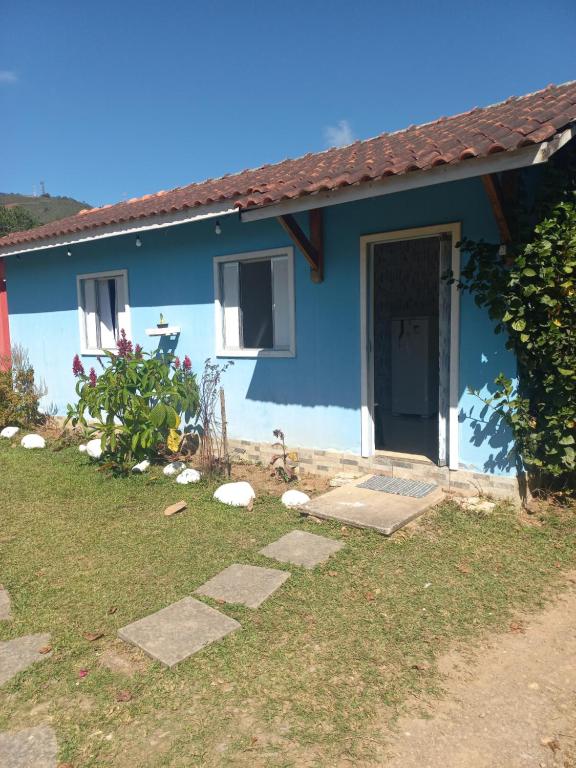 a blue house with a dog standing in front of it at Pousada Maia em Flor chale azul in Resende
