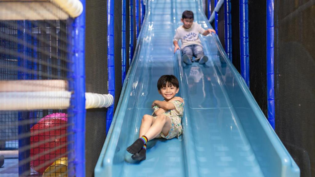 two young boys are riding down a slide at Holiday Inn Pattaya by IHG in Pattaya