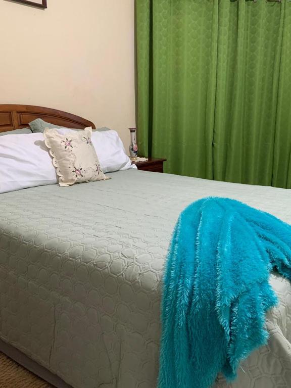 a bed with a blue blanket on top of it at The Cozy Haven Bed and Breakfast in Montego Bay