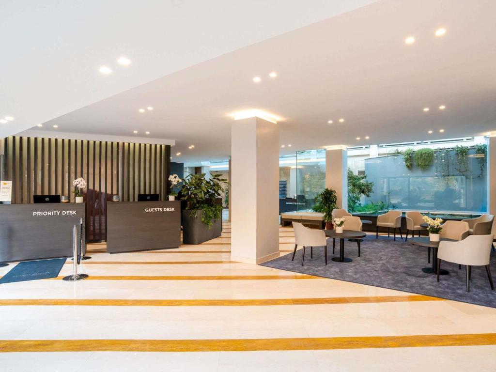 a lobby with tables and chairs in a building at Mercure Roma West in Mostacciano