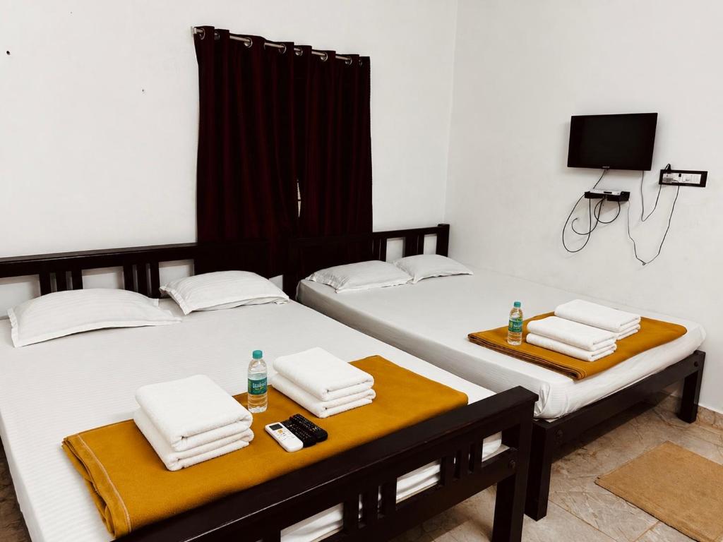 two twin beds in a room with a tv at AURO BAY inn in Kuilapayam