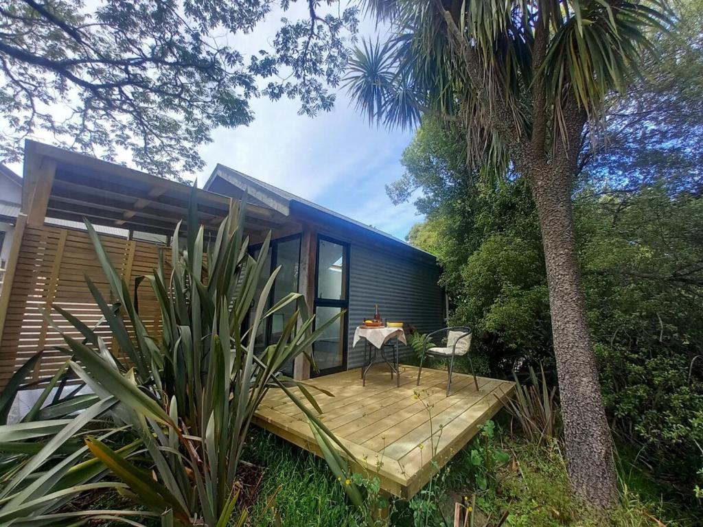 a blue house with a deck and a palm tree at Mapua Cabbage Trees in Mapua