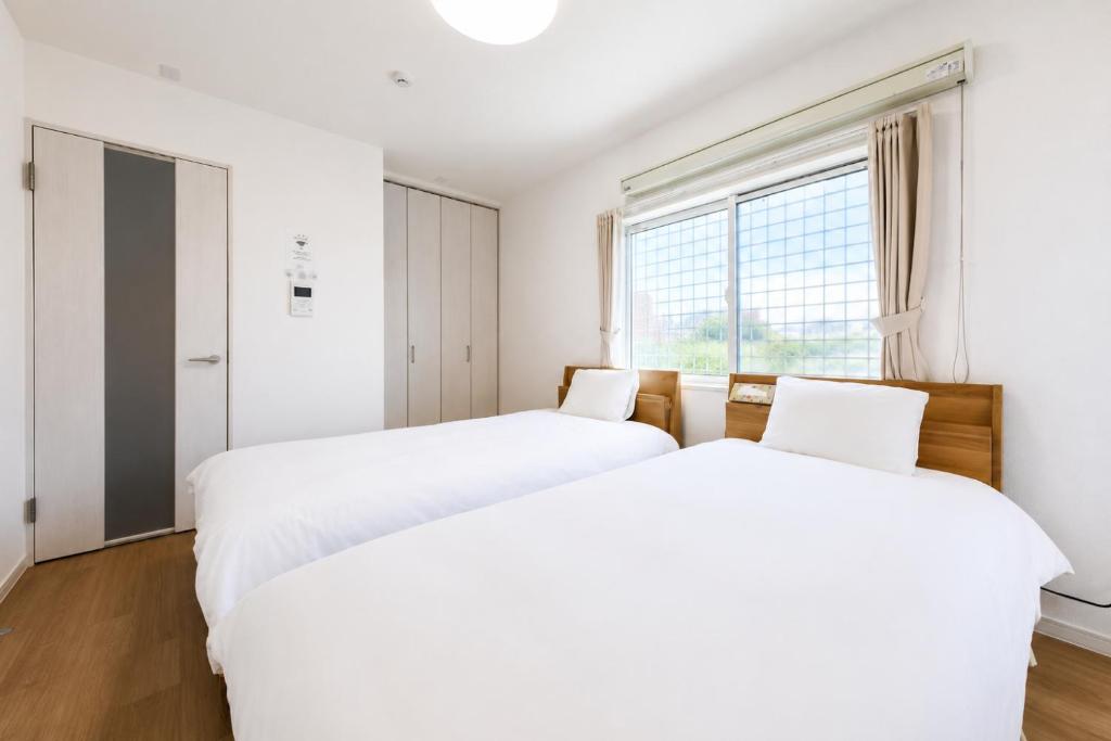 two beds in a room with a window at BALOH Wadamisaki in Kobe