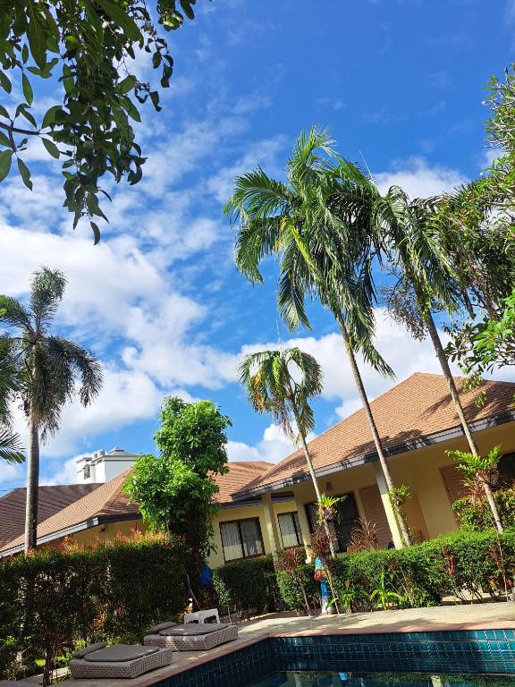 a house with palm trees and a swimming pool at Happy Cottage in Chalong