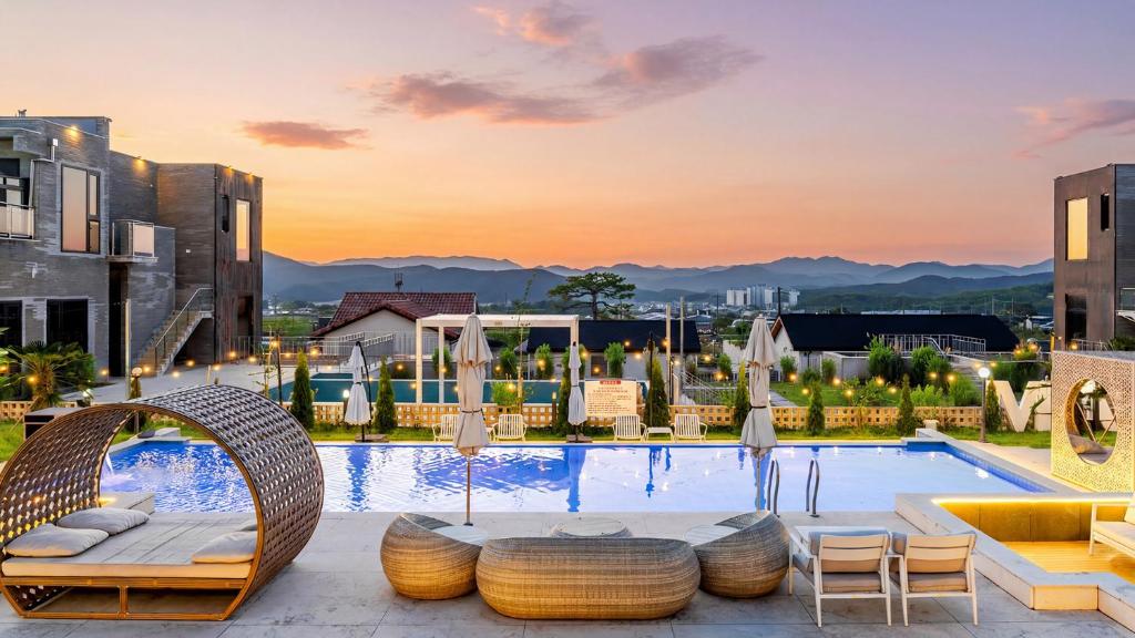 a pool at a hotel with chairs and umbrellas at Gyeongju heybreeze Pool Villa in Gyeongju