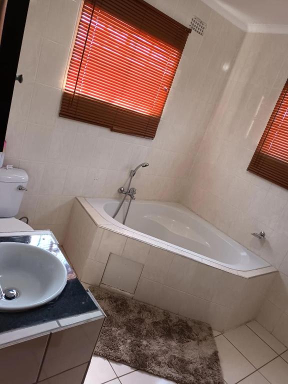 a white bathroom with a tub and a sink at Pleasant Field Bed And Breakfast in Gaborone