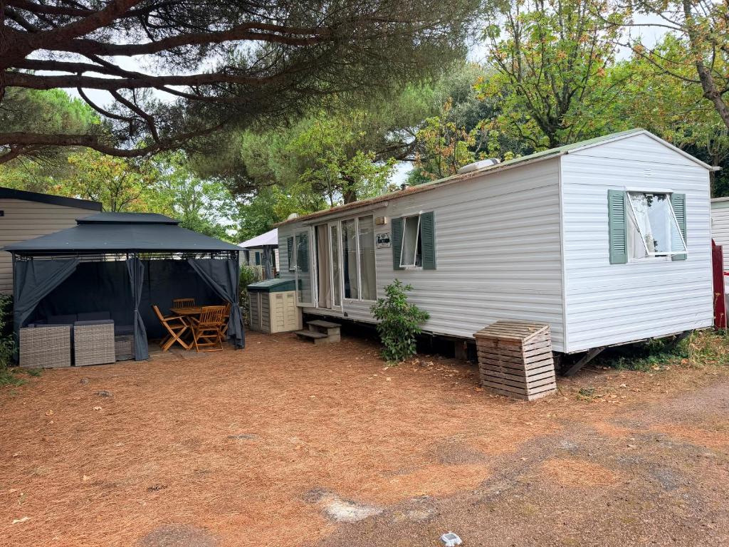 a white trailer with a tent and a table at Mobile Home WT 1906 in Saint-Pierre-dʼOléron