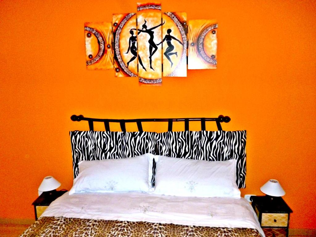 1 dormitorio con una pared de color naranja, 1 cama y 2 cuadros en I Cinque Continenti en Palermo