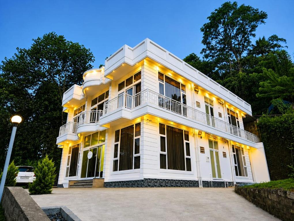 a large white building with a balcony at Uforia Munnar in Munnar