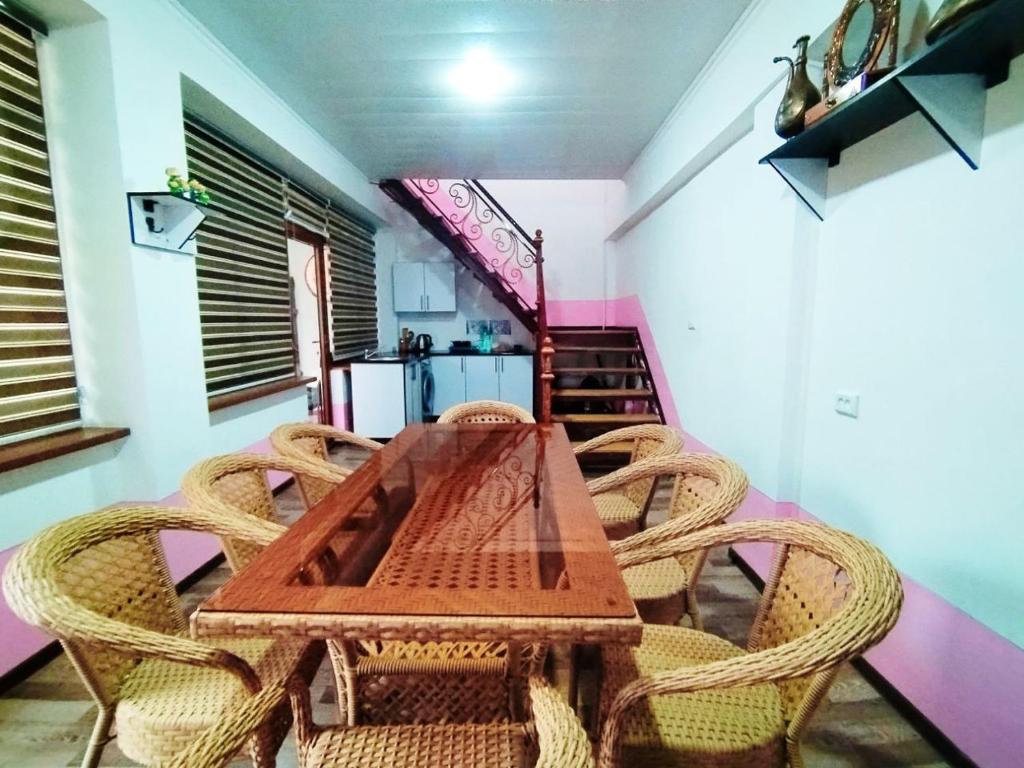 a dining room with a wooden table and wicker chairs at Hostel Joyzar in Bukhara