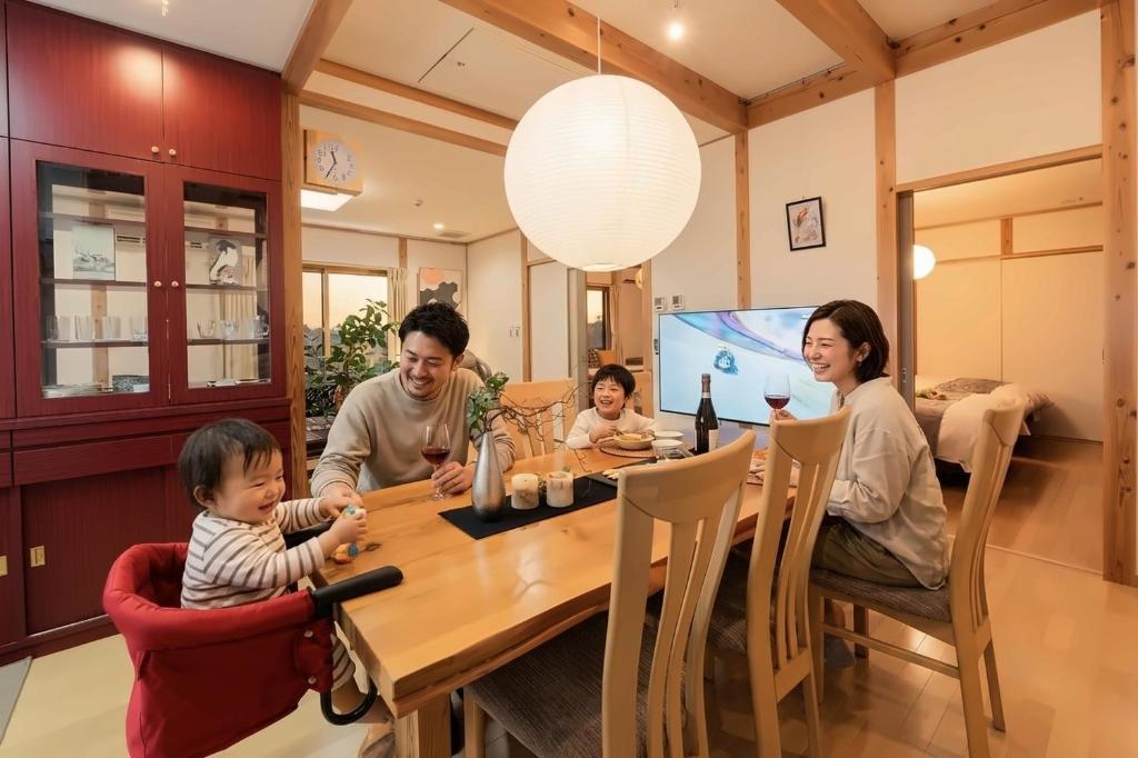 a family sitting around a wooden table in a dining room at Cove琴平 - 1組貸切 最大8名 こんぴらさん徒歩すぐ in Kotohira