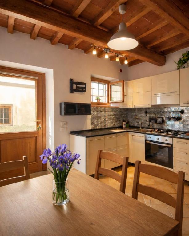 una cucina con un tavolo di legno con sopra dei fiori viola di Casina Iris - Reggello a Reggello