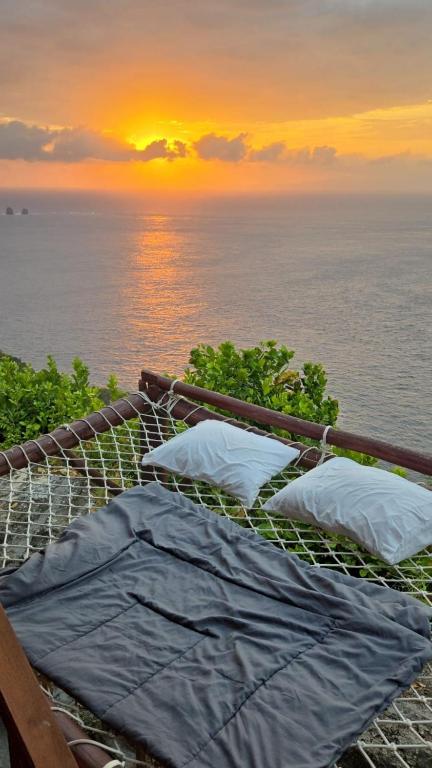 a hammock with a view of the ocean at sunset at Suwehan Beach Cliff House with Hammock in Polilit