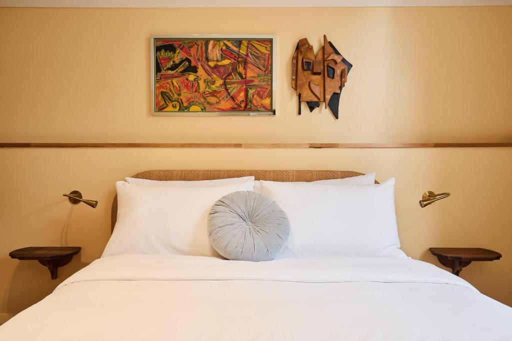 a bedroom with a white bed with a painting on the wall at Darlo Bar Darlinghurst in Sydney