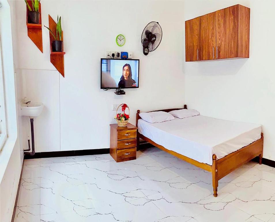 a bedroom with a bed and a tv on the wall at Himali Niwasa in Matara