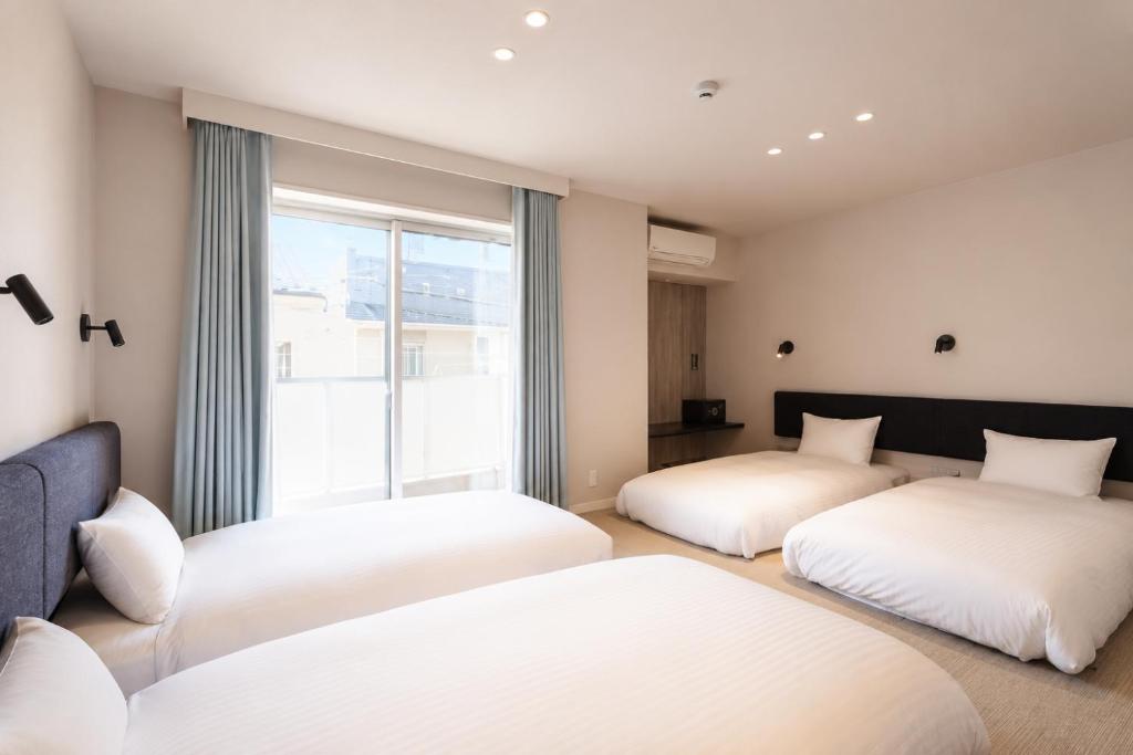 two beds in a room with a window at 5 minutes Shin-Osaka 9 in Osaka