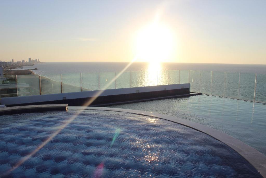 a swimming pool on the roof of a building with the sunset at Apartmento Edificio Porto Vento in Cartagena de Indias