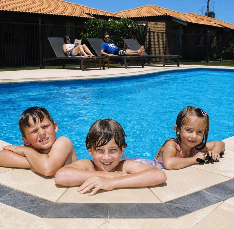 three children laying in a swimming pool at Geraldton's Ocean West Holiday Units & Short Stay Accommodation in Geraldton