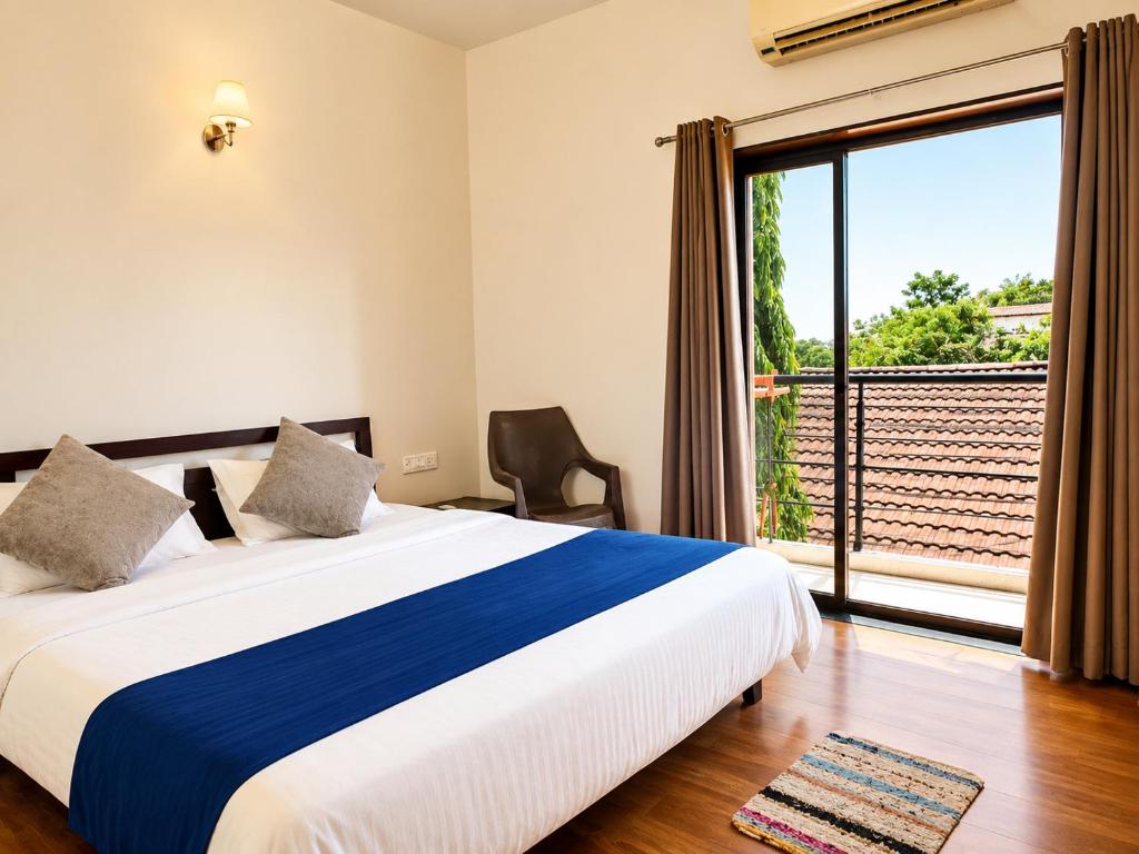 a bedroom with a bed and a large window at Hotel Maurya Regency in Morjim