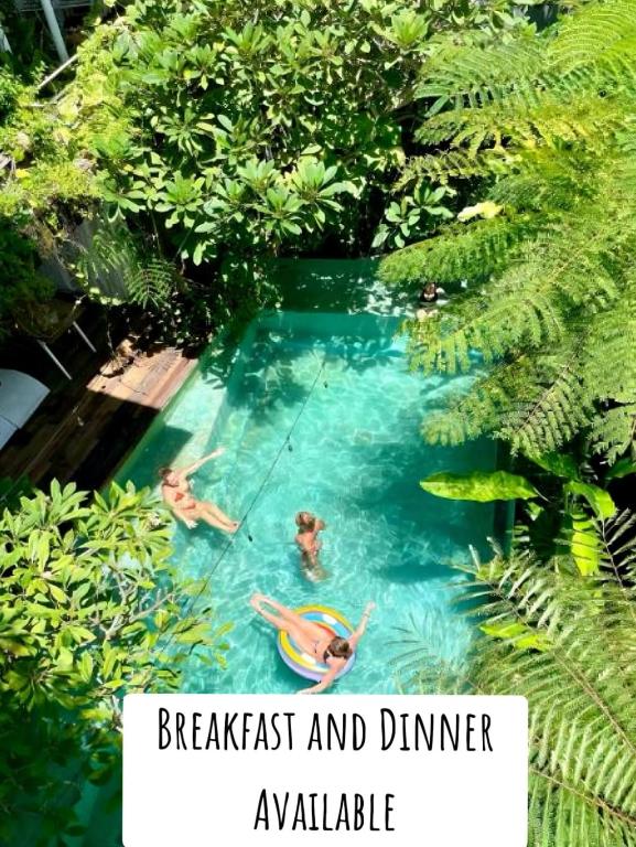 two people swimming in a swimming pool with trees at The Hide Hostel Canggu in Canggu
