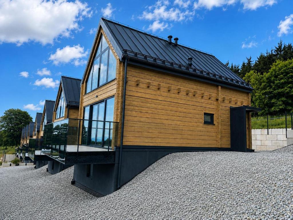 a large wooden house with a black roof at Góry i Chmury in Duszniki Zdrój