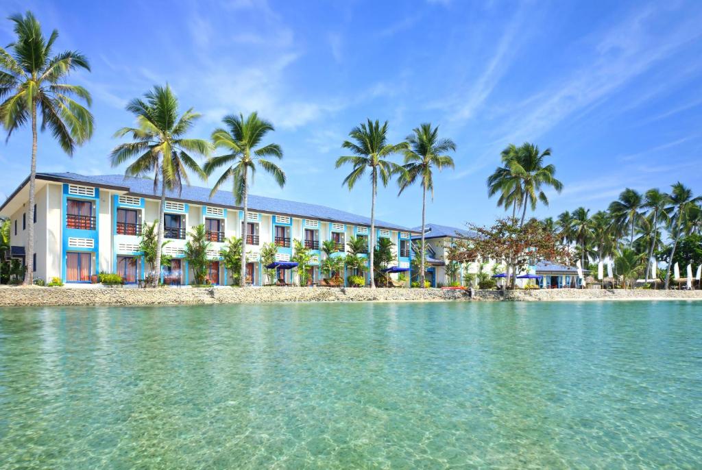 a hotel on the beach with palm trees at Microtel by Wyndham Puerto Princesa in Puerto Princesa City