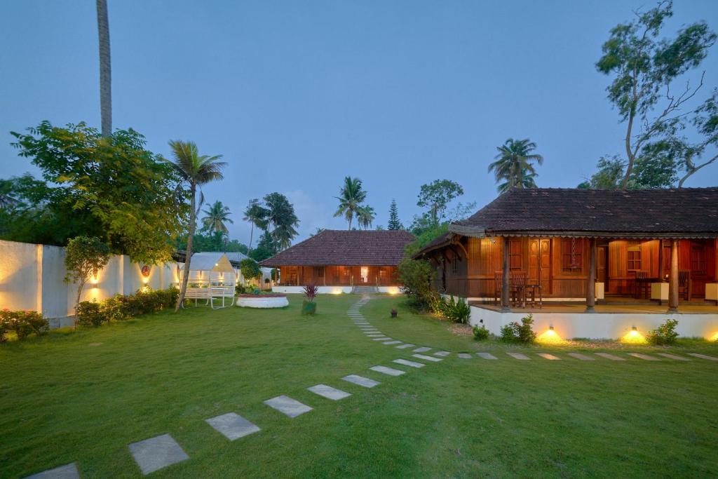 a house with a grass yard next to a building at Deshadan's Tarangi Beach Villas,Marari in Mararikulam