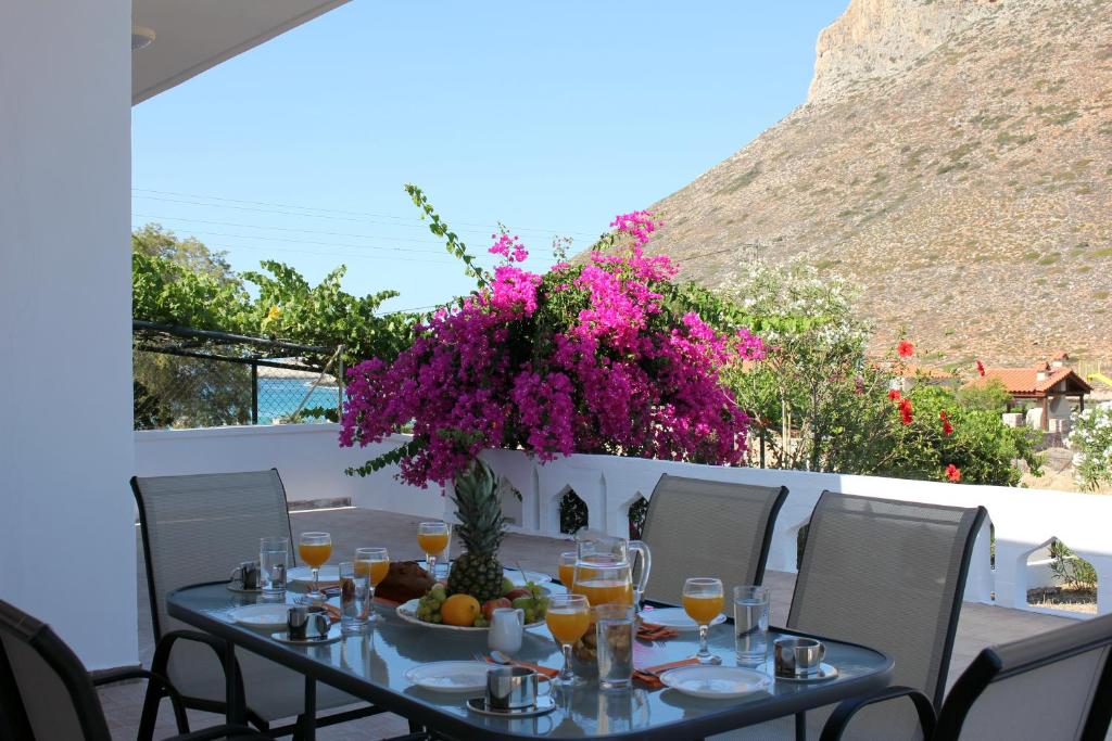 a table with a vase of purple flowers on a balcony at Theros Beach House in Stavros