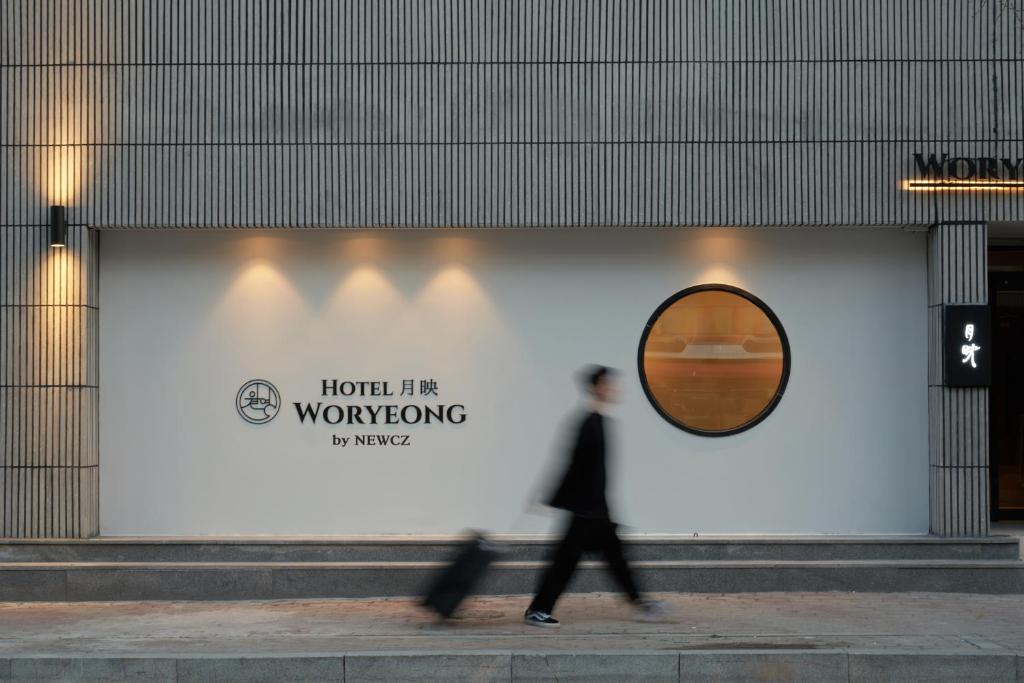 a man walking down a sidewalk in front of a building at Wolyoung Hotel By NewCZ in Andong