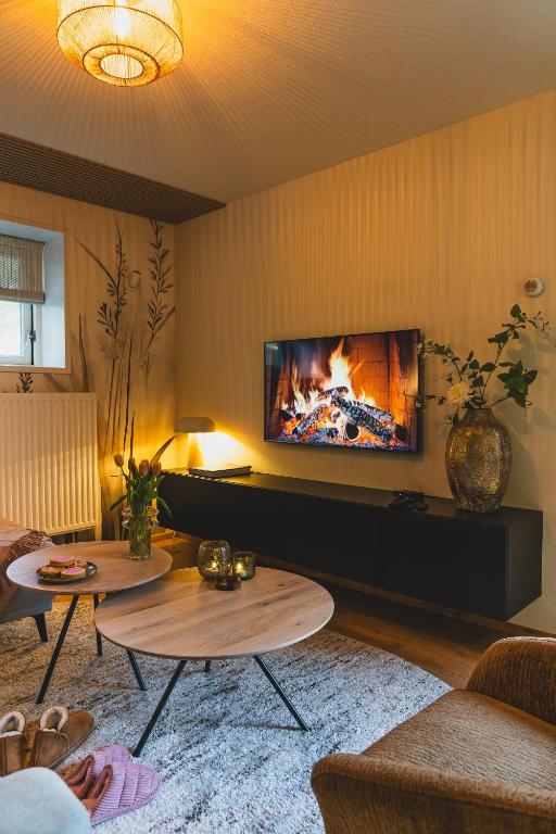 a living room with two tables and a fireplace at Stijlvol 4-6 pers "Vakantiehuis De Meierij" - compleet ingericht huis met vrij weidezicht in Schijndel