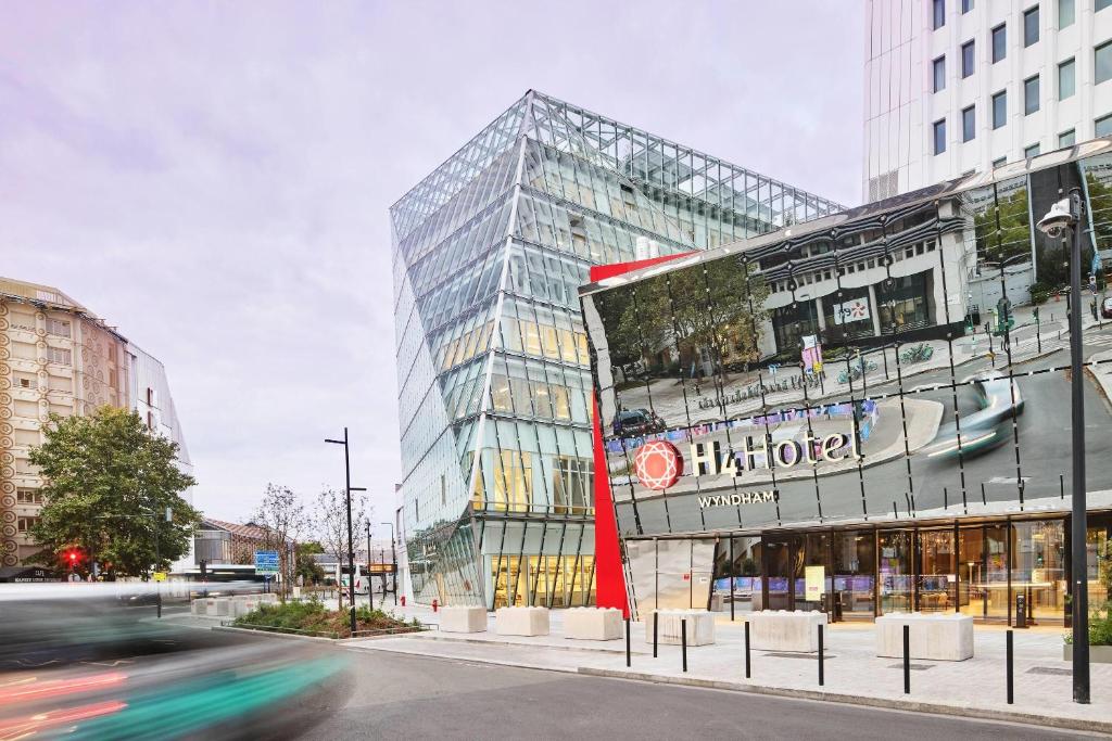 a glass building with a sign on the side of it at H4 Wyndham Paris Pleyel in Saint-Denis