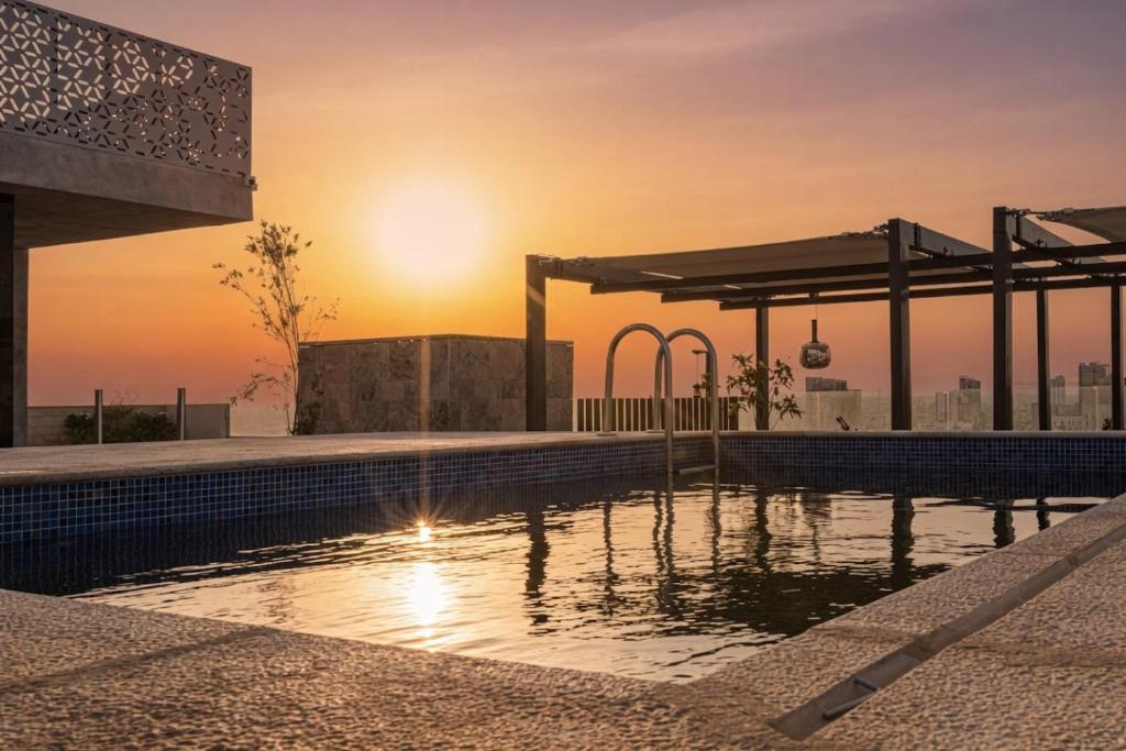 a pool on the roof of a building with the sunset at Stella Stays Olaya Tower 1 - Furnished Apartments in Riyadh