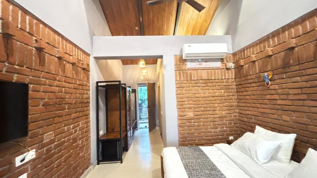 a room with a brick wall and a bed and a tv at Hide Away Resort in Jhārgrām