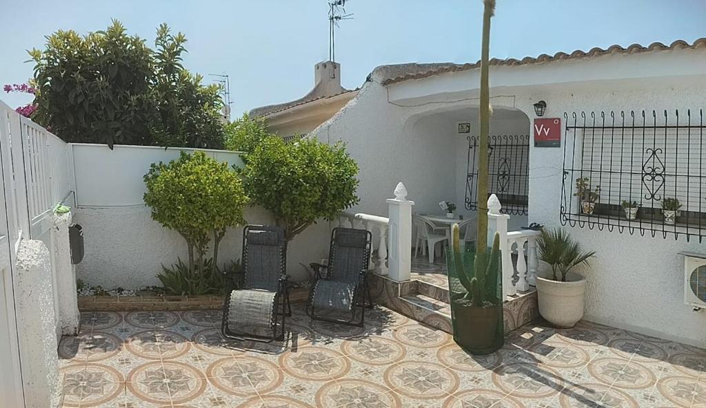 a patio with chairs and a fence and a house at El Rincón del Sotillo beach in Los Alcázares