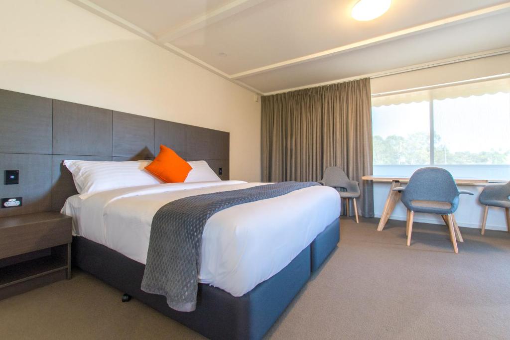 Hackham的住宿－米克奧西斯酒店，酒店客房设有一张大床和一张书桌。