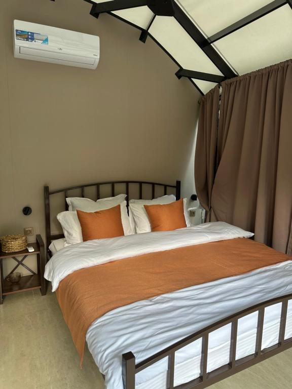 a bedroom with a bed with orange and white pillows at Ugam Glamping in Khumson