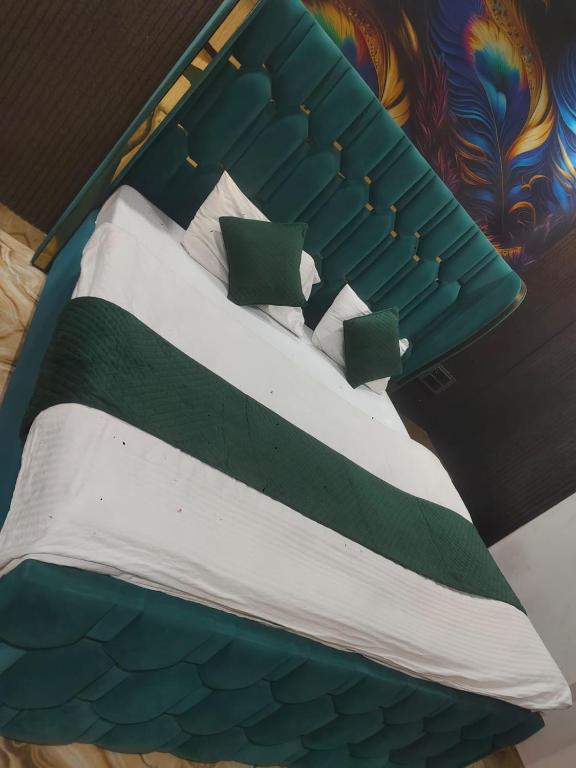 a bed with green and white sheets and pillows at Hotel Ienvo Inn in New Delhi