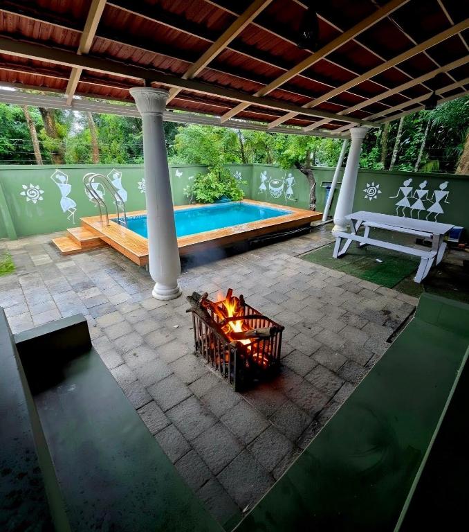 a patio with a fire pit and a pool at White Cloud Stay Attappadi in Agali