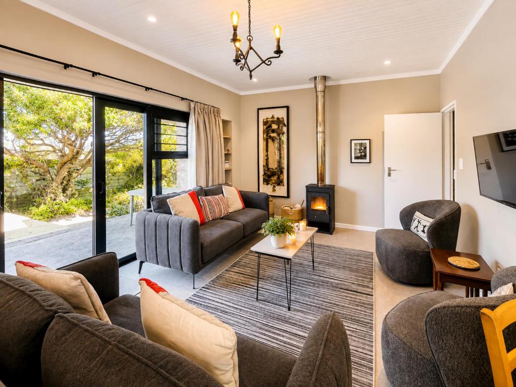 a living room with a couch and chairs and a tv at Sandy Toes Home in Plettenberg Bay