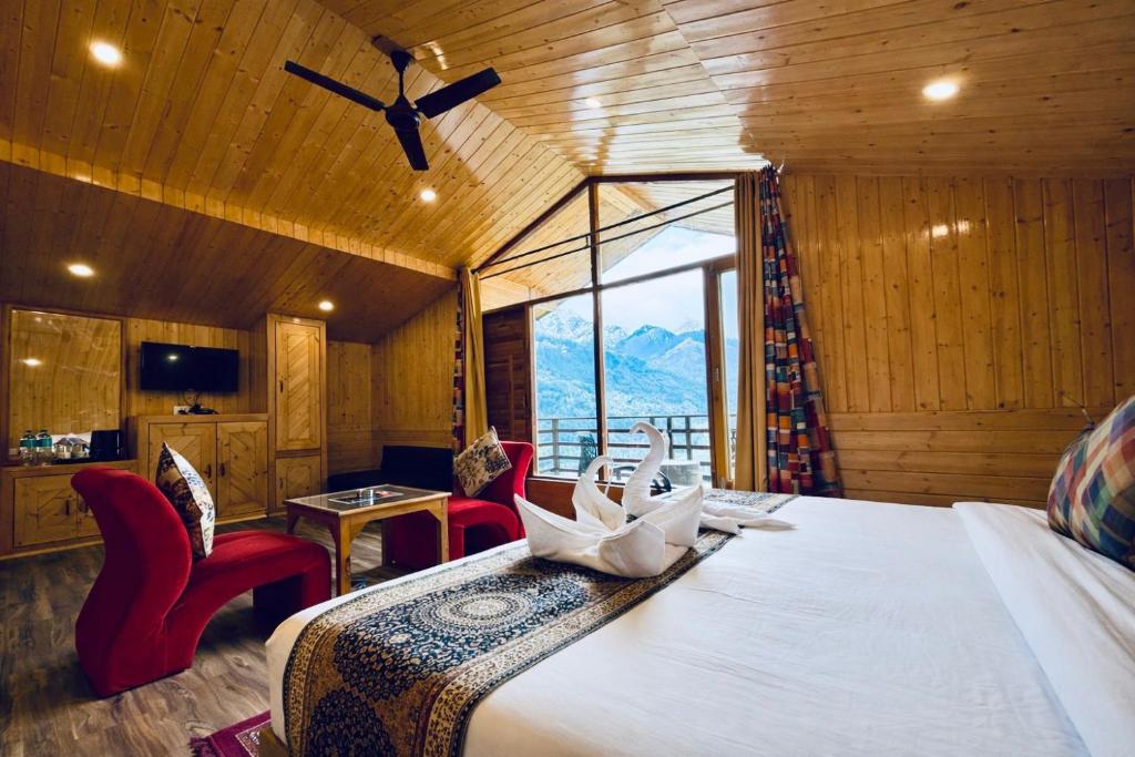 a bedroom with a bed with chairs and a large window at Hotel Mount Manali - The Cozy Stay in Vashisht