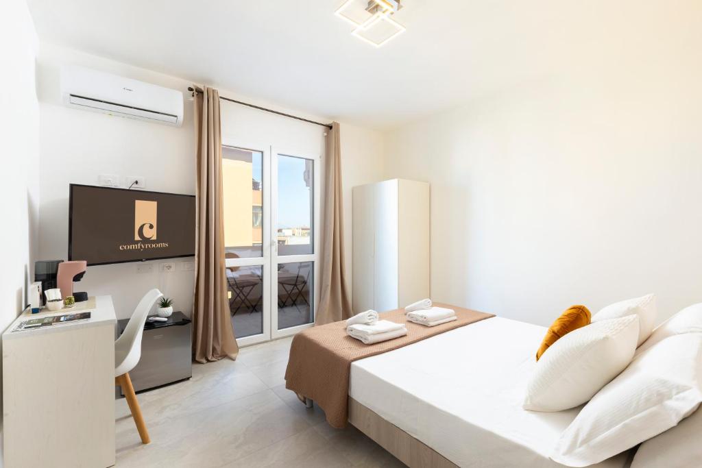 a white room with a bed and a television at Comfyrooms in Quartu SantʼElena