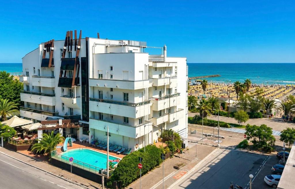 an apartment building with a swimming pool next to the ocean at Hotel Executive La Fiorita in Rimini