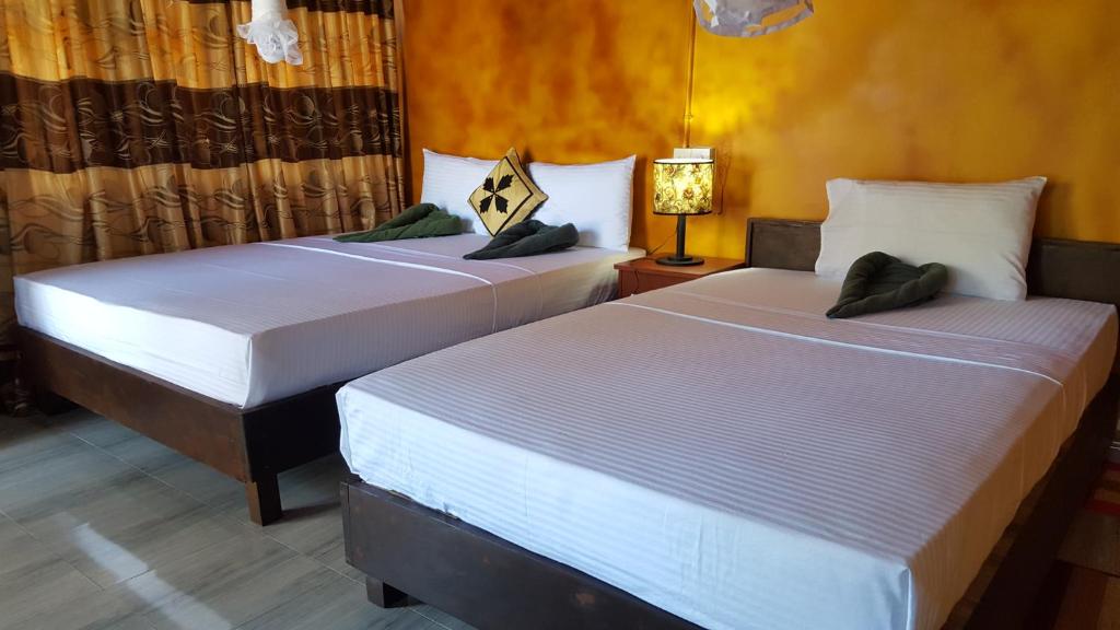 2 camas en una habitación de hotel con lámpara en Riverside Lal Homestay, en Sigiriya
