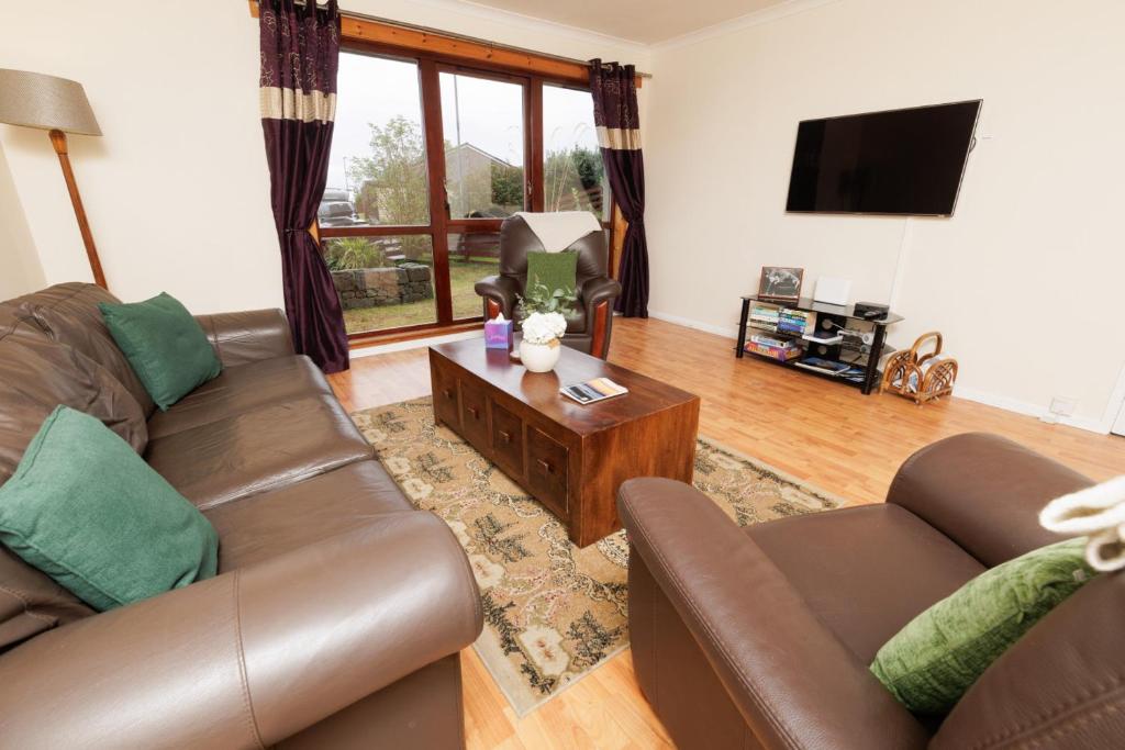 ein Wohnzimmer mit zwei Sofas und einem Fernseher in der Unterkunft Millbrae, Shetland Islands in Lerwick