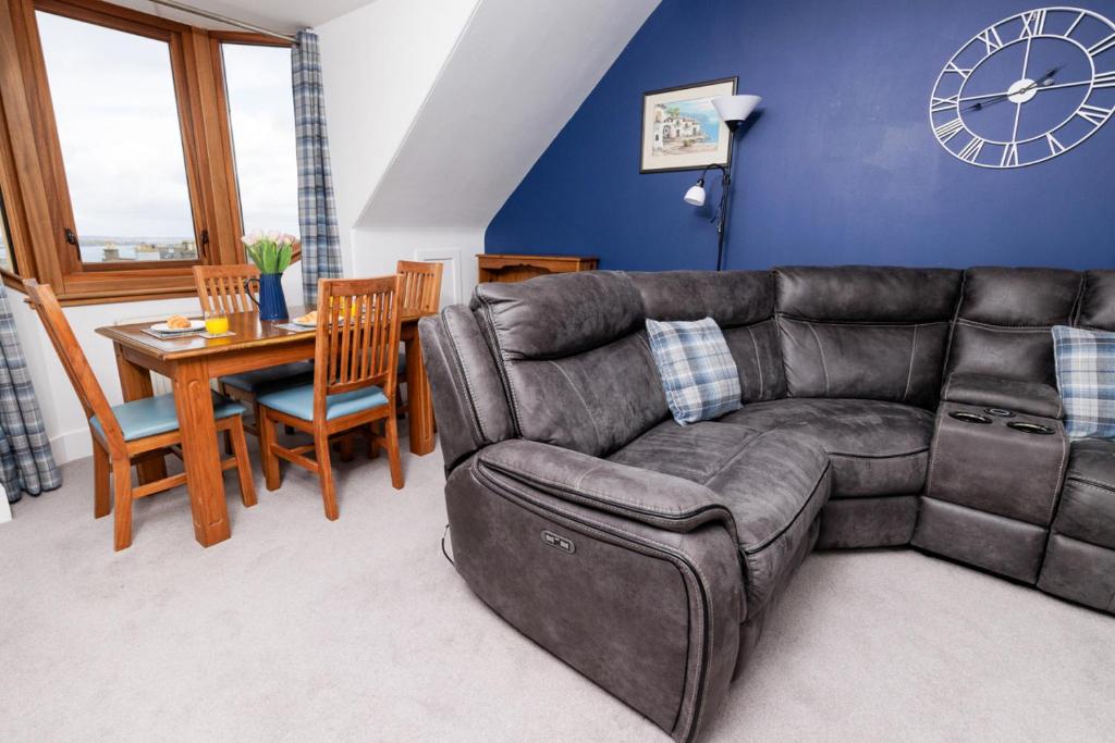 a living room with a leather couch and a table at North Harbour View, Shetland Islands in Lerwick
